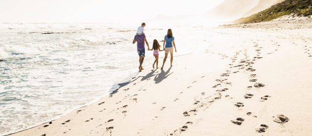Familie läuft gemeinsam am Strand entlang